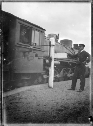 Changing the tablet at Horopito Railway Station, with an "X" class locomotive passing.