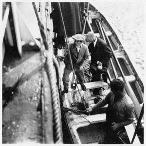 Men standing in a surf boat at the side of a ship