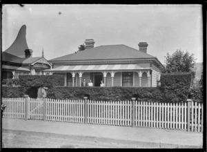 Laura Godber with her two children, Phyllis Mary and William Albert, standing on the verandah of their house, Railway Whare, at 23 Bay Street, Petone