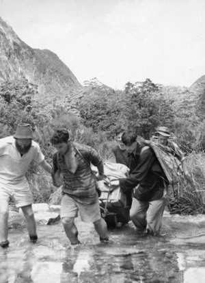 Men transporting an electric generator along the Milford Track, from Glade House to Pompolona
