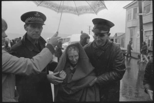 Elderly woman, a survivor from the Wahine shipwreck being assisted by a policeman and Salvation Army Captain David Bennett