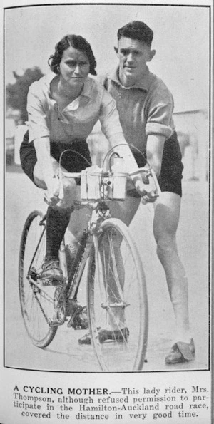 Woman seated on a bicycle with a man holding her steady