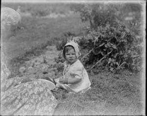 An unidentified child and older woman (possibly Laura Godber) seated in a garden