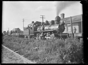 Private line bush locomotive (Mallett) beside a station with a board advertising the Taupo Totara Timber Company