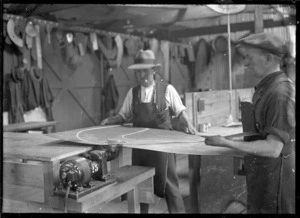 Interior view of the tinsmiths' shop at the Hillside Railway Workshops, Dunedin, showing two men shaping and cutting tin.