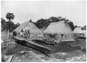 Children standing on an outrigger canoe in a Fijian village