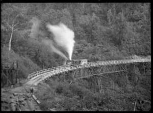 Climax steam locomotive, number 1650, hauling empty logging wagons on a railway viaduct near Ongarue