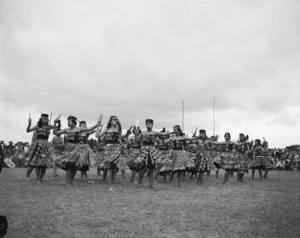 Burns, G, fl 1958 (Photographer) : Women performing an action song with patu at centenary celebrations of the King Movement, Turangawaewae Marae, Ngaruawahia