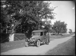 Laura Godber standing beside a touring car, in Whiteman's Valley Road, Silverstream