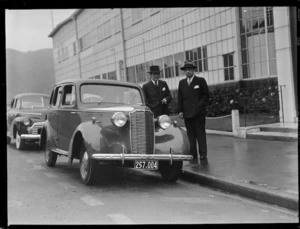 Two men standing beside parked Vauxhall 14 car