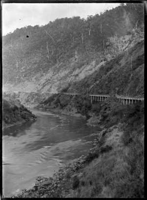 View of the railway line with retaining walls, running along the side of the Manawatu River in the Manawatu Gorge, at the Woodville end