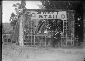 A man wearing a uniform, seated in front of a sweet stall