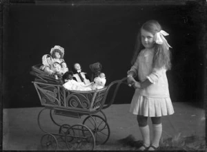 An unidentified young girl with a toy pram filled with dolls