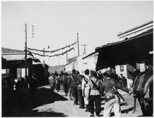 Well armed partisans marching through a village near Athens