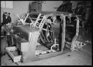 Men working on the shell of a car body in a workshop