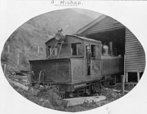 Albert Percy Godber standing in the cab of Wd class steam locomotive (NZR number 318), which has crashed through the wall of a railway shed