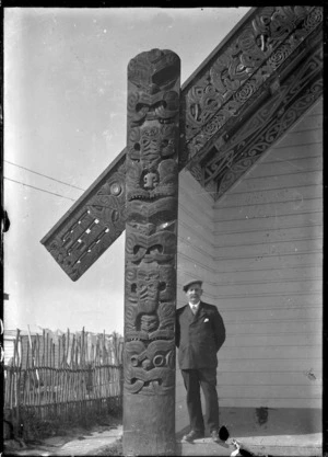 Albert Percy Godber standing beside the amo (barge-board support) at Te Ao Marama meeting house, Ohinemutu.