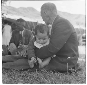 Elderly Maori man holding a Maori infant, Koroniti