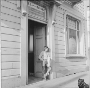 Young Indian boy selling newpapers outside a bottle store in Vivian Street, Wellington