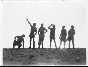 Group of New Zealand soldiers watching aircraft at sunset, Western Desert, during World War II