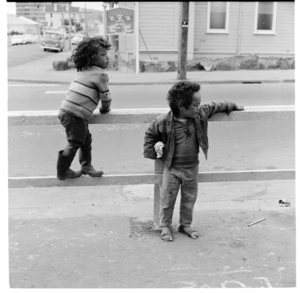 Two young Maori children, and, children playing games at a table in a room, 1974.