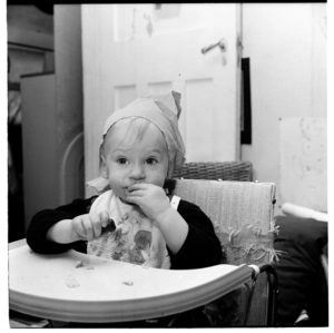 Lisa van Hulst wearing a party hat, sitting in a high chair, probably on her 1st birthday