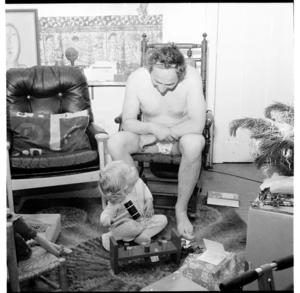 Lisa van Hulst and her father opening parcels at Christmas time, and, families at houses (possibly in the Mount Cook area), Wellington