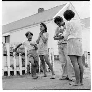 Four young Māori outside a house in the Mount Cook area, an older boy holding a white cat