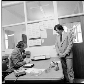 Two men in an office, using a desktop printer