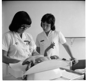 A nurse checking and weighing a newborn baby in hospital