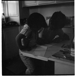 Child at a desk in a kitchen with an older person marking some work; and, scenes in Wellington
