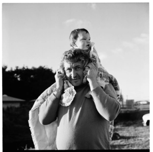 Children playing ball at Waikanae Beach, and a man carrying his toddler on his shoulders