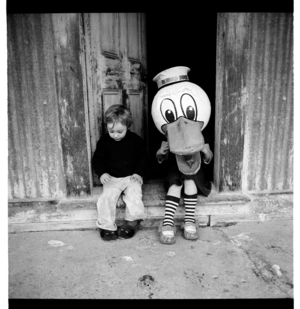 Two young children wearing a large Donald Duck mask