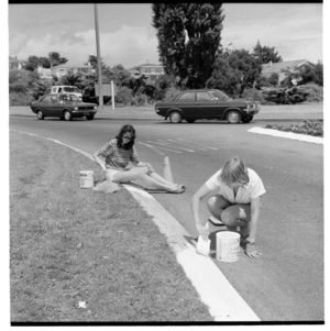 Young women painting a kerb white