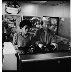Two boys playing a speed race game in an amusement arcade, probably in Auckland
