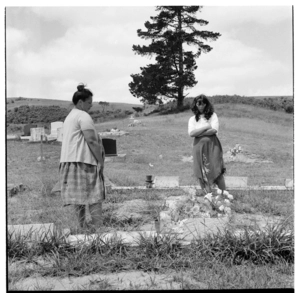 Women tending a grave at an unidentified cemetery, possibly in the Far North of New Zealand