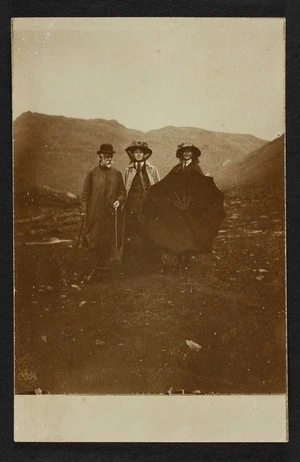 One man and two women, one possibly Mary Vida Pearce, standing in a barren landscape