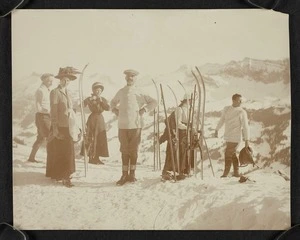 Group of men and women on the top of a hill, with skis and poles propped up beside them, Switzerland
