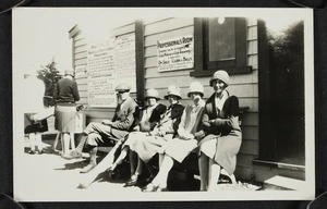 Agnes Isobel Stout and other spectators seated outside a golf pavilion