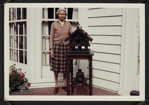 Agnes Isobel Stout with carved Maori artefacts on the porch of her house