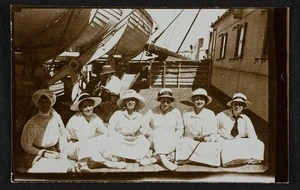 Six young women sitting cross legged on the deck of a ship