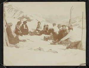 Group sitting in the snow beside a building, Switzerland