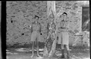 Sgt L barton and R L Kay beside Maori carving on a tree in the village of Suani Ben Adem, Libya - Photograph taken by W Timmins