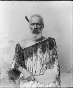 Maori man wearing korowai and carrying a mere