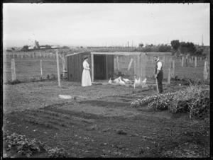 Man and a woman alongside a vegetable garden and a chicken run