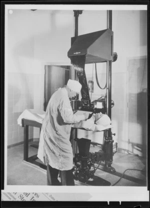 Radiographer performing a chest X-ray on woman