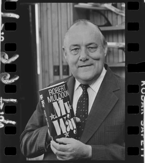 Prime Minister Robert Muldoon holding up a copy of his third autobiography - Photograph taken by Don Scott