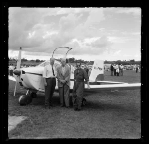 Victa aircraft (VH-FMM) on the ground with Leo Lemuel White and two unidentified men (one of whom is the pilot) in front of the plane, Mangere, Manukau City, Auckland