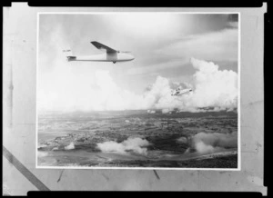 Glider ZK-GBM flying over [Auckland?] with another plane flying upside down in the background