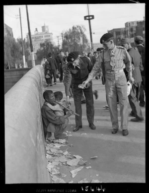 New Zealand J Force soldiers giving money to a blind street musician, Tokyo, during the allied occupation of Japan after World War II